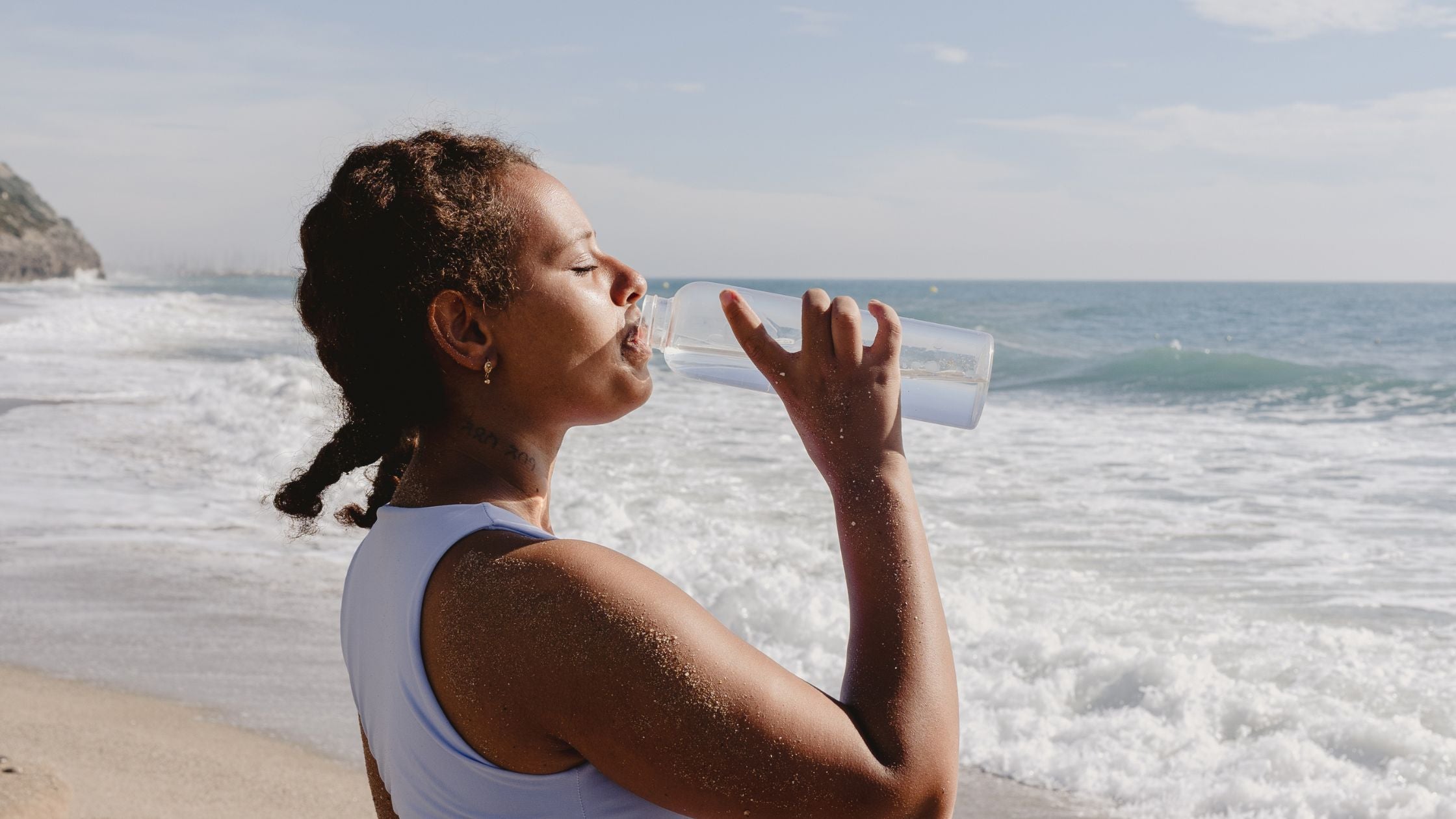 lady drinking water by the ocean